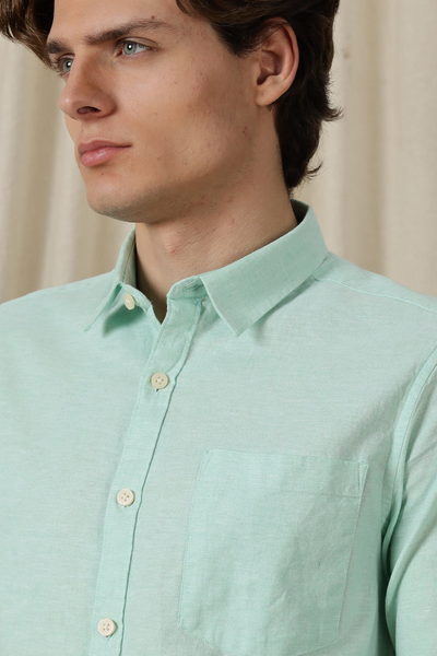 Man wearing a light green shirt with a neutral background