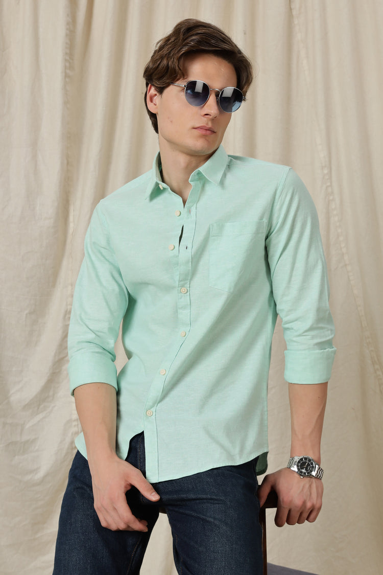 Man wearing a light green shirt and sunglasses against a beige background