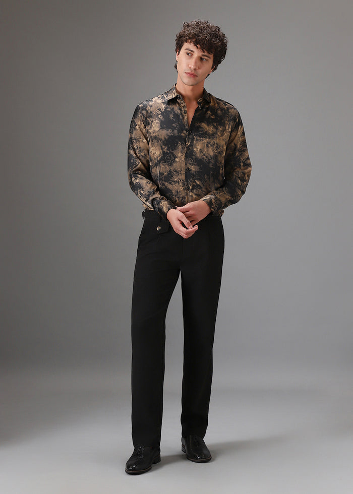 Man wearing a patterned shirt and black pants against a gray background