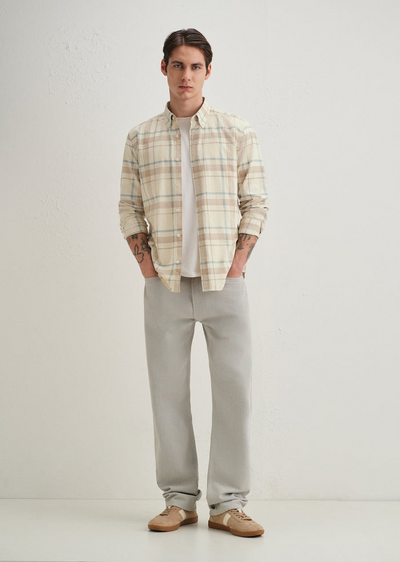 Man wearing a plaid shirt and light gray pants on a white background